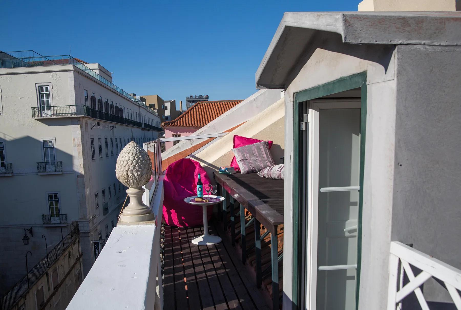 Una terraza en la azotea con asientos al aire libre y cojines coloridos junto a una puerta abierta.