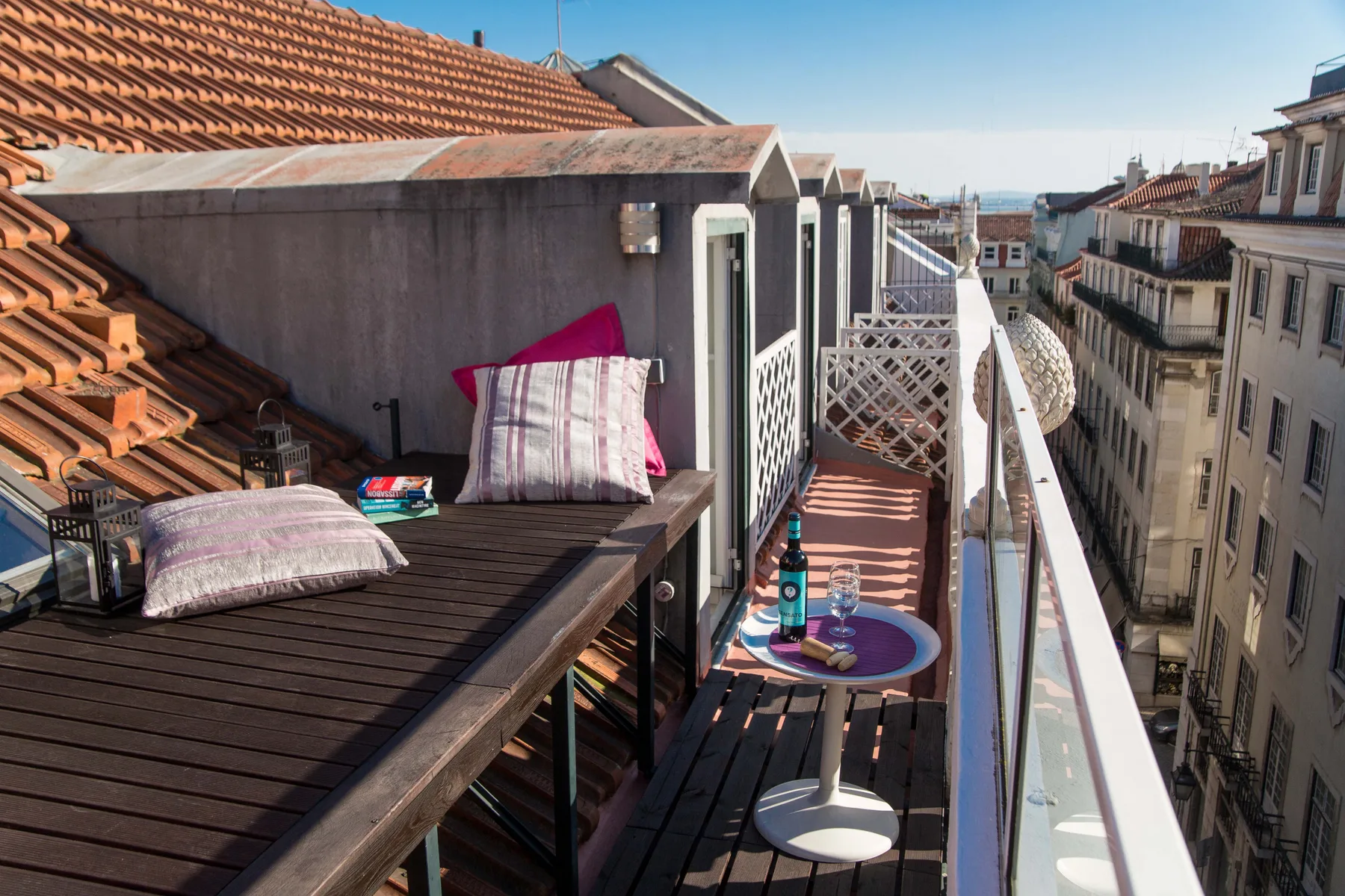 A narrow rooftop terrace with outdoor seating and views of nearby buildings.