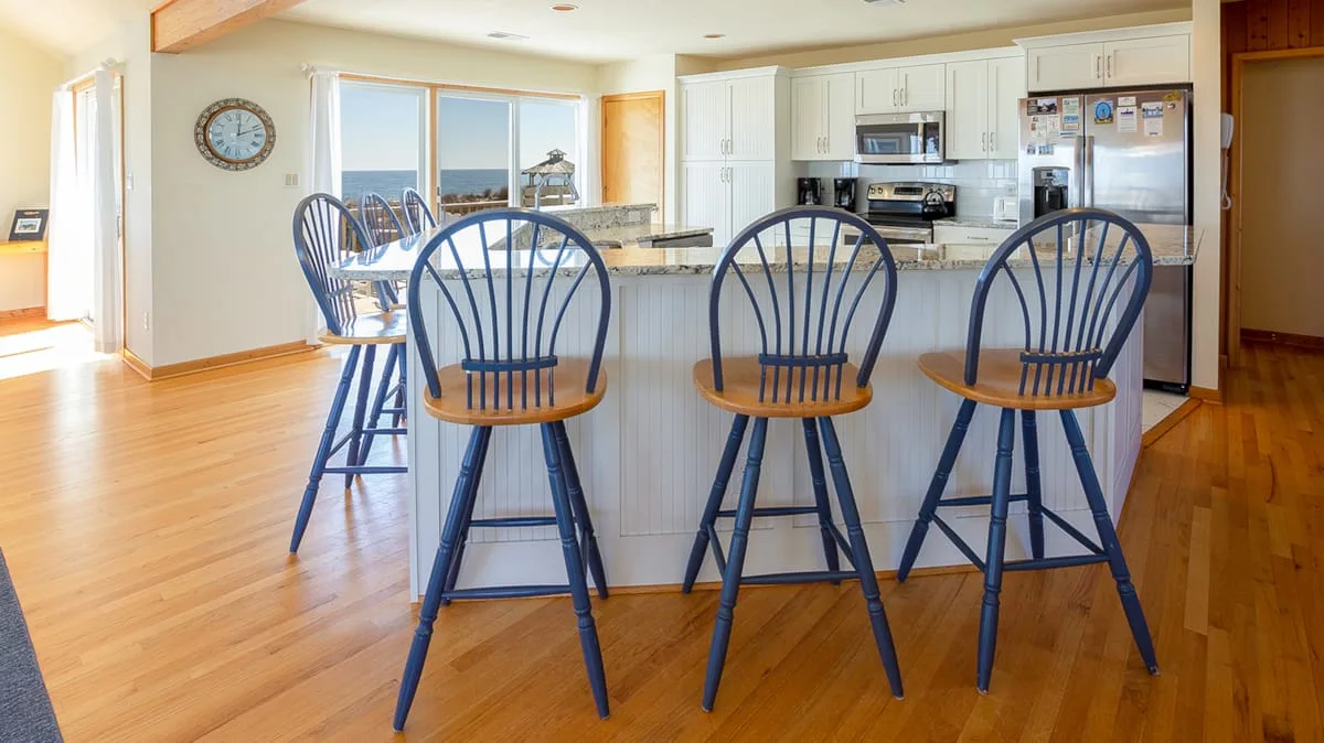 A bright kitchen with a central island and blue bar seating.