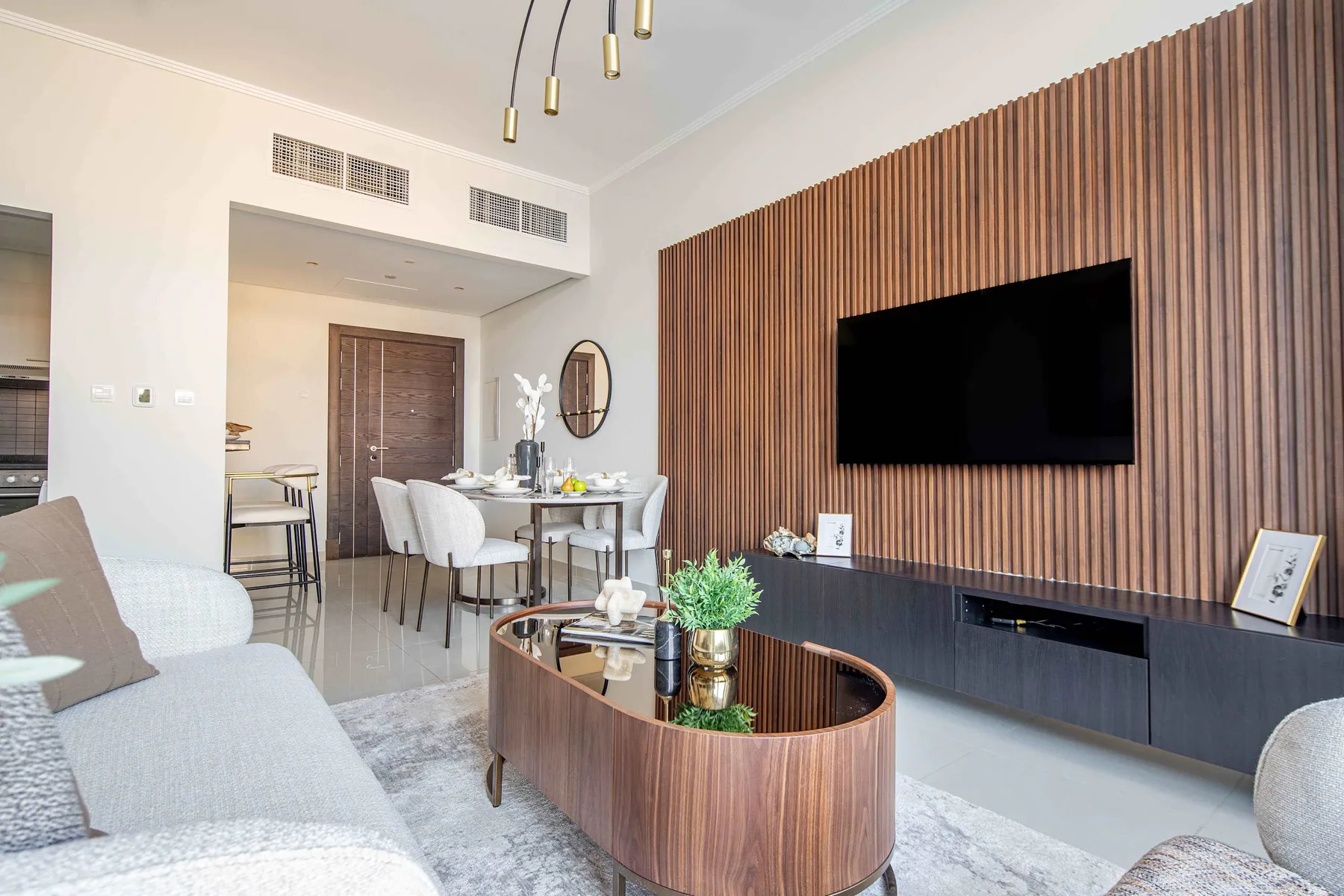 A modern living room with a dining area and a wall-mounted television.