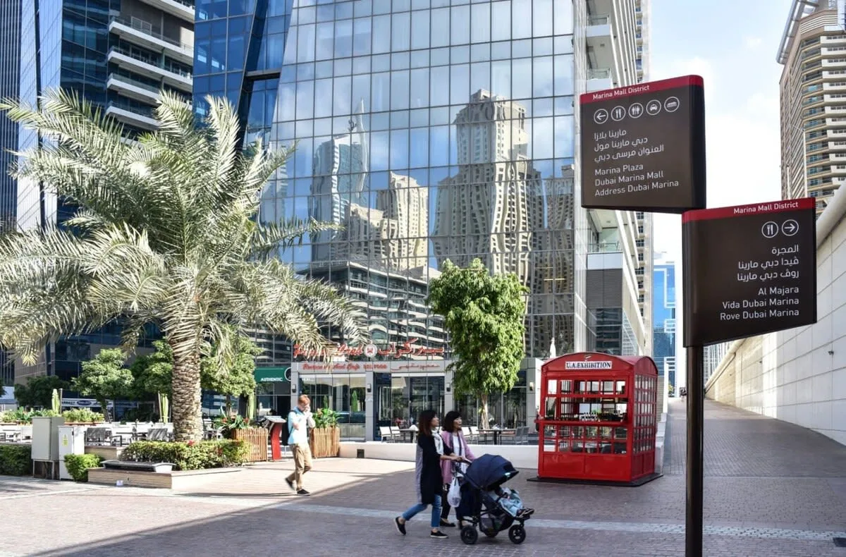 A pedestrian plaza with a red kiosk in front of glass office buildings.