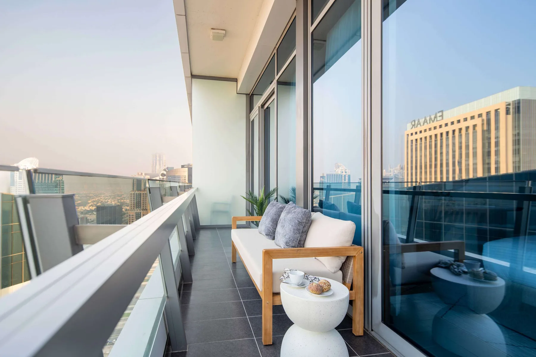 A narrow balcony has a cushioned bench beside floor-to-ceiling glass doors.
