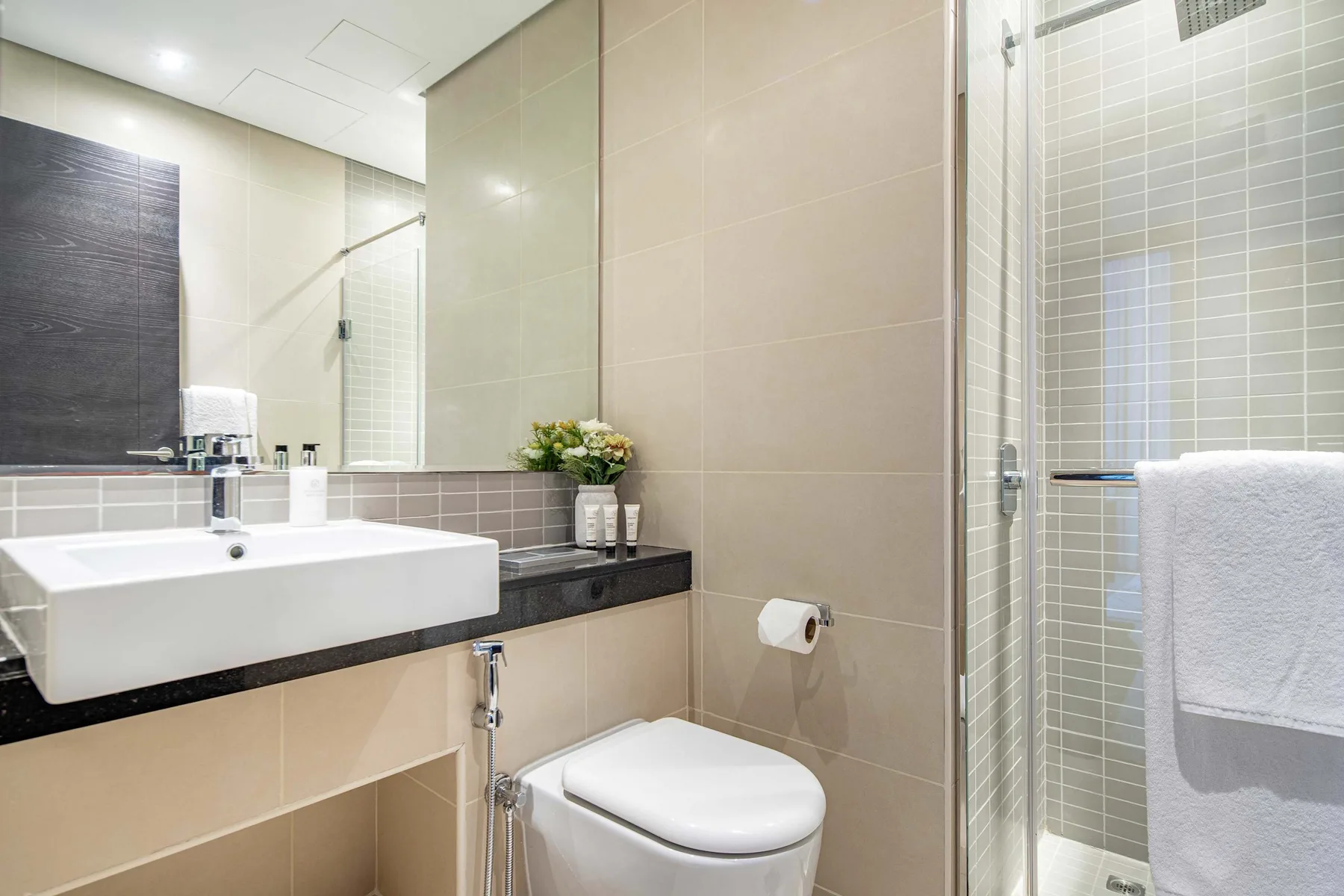 A tiled bathroom with a sink, toilet, and glass shower.