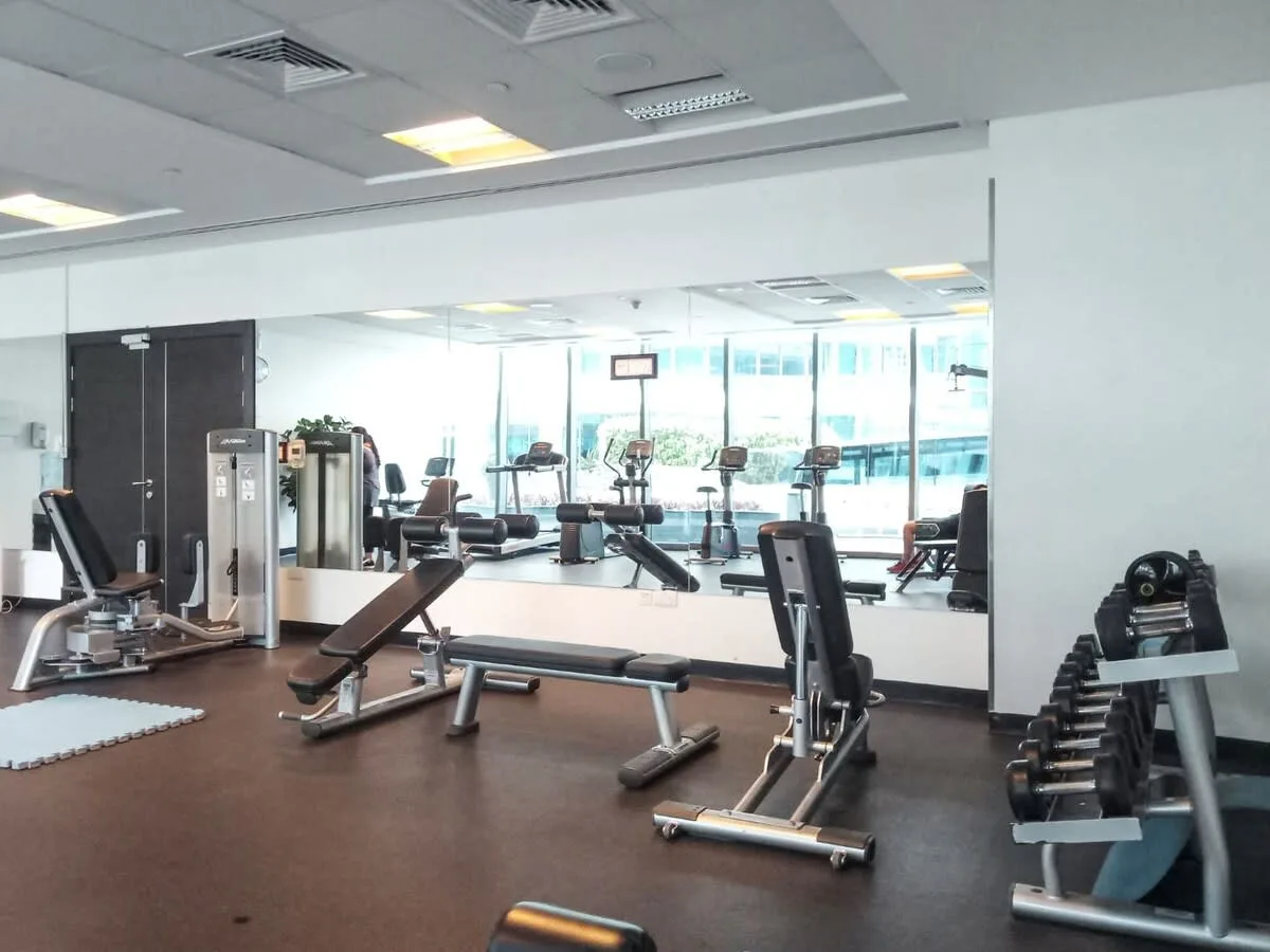 A gym with weight-training equipment and a large wall mirror.