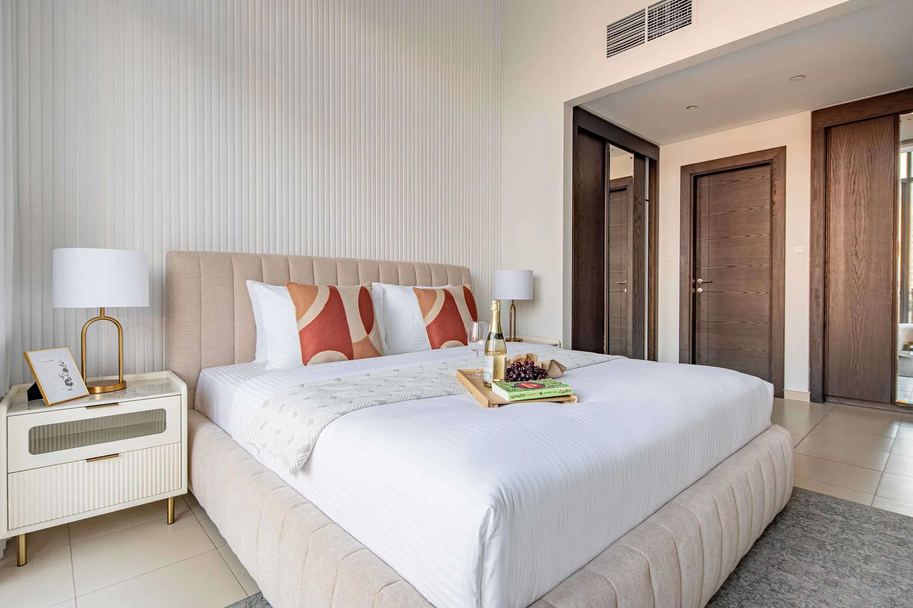 A bedroom with a large bed, patterned pillows, and bedside tables.