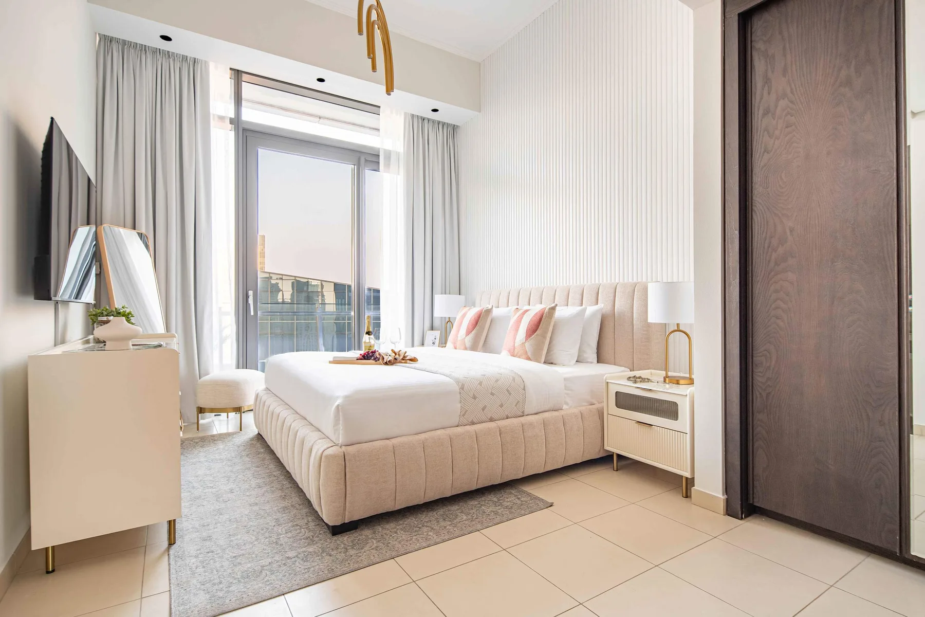 A bright bedroom with a bed, bedside tables, and a large window.