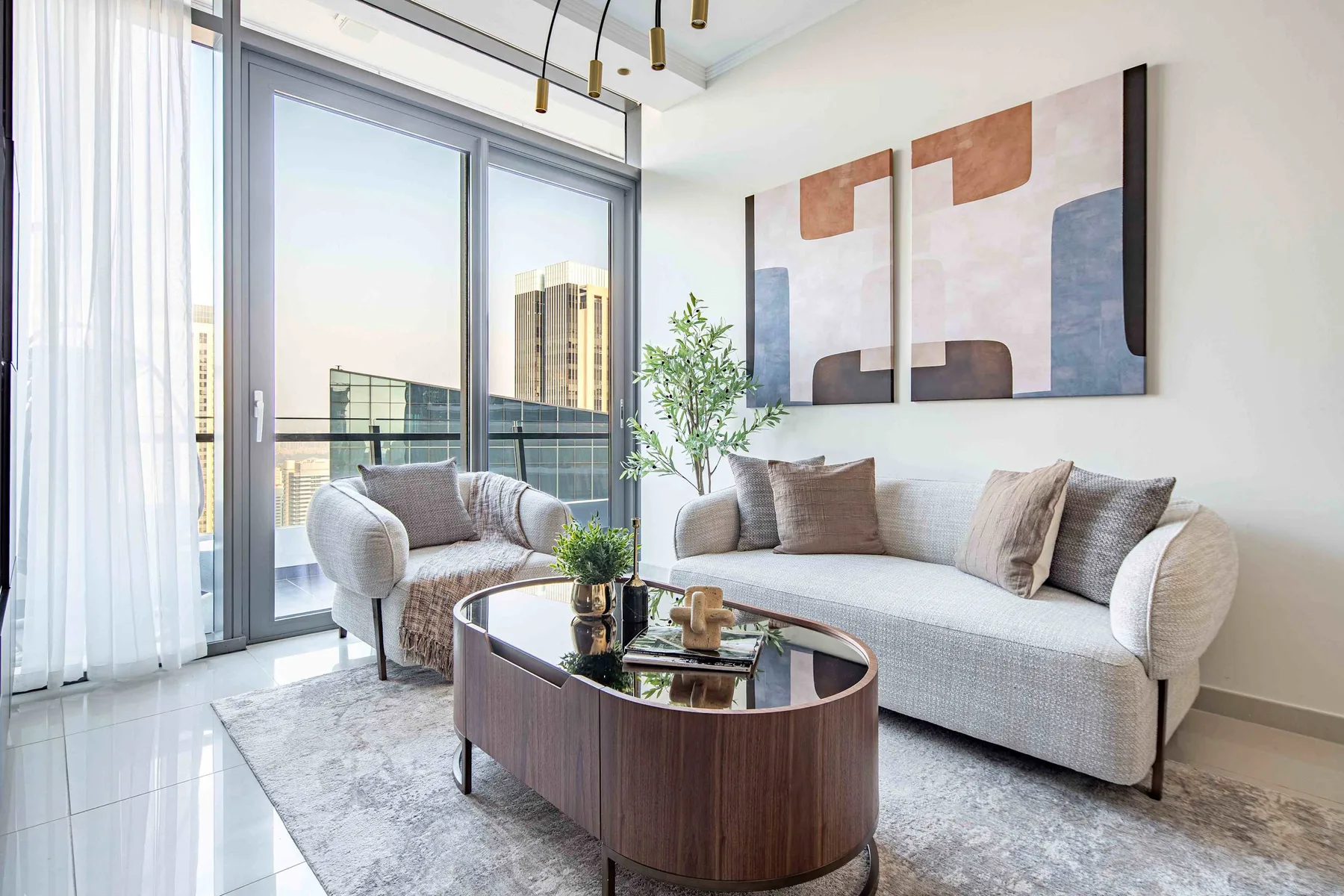 A bright living room with seating beside large windows overlooking city buildings.