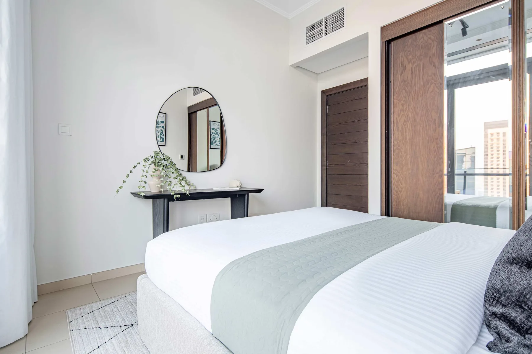 A bright bedroom with a neatly made bed and a small console table.