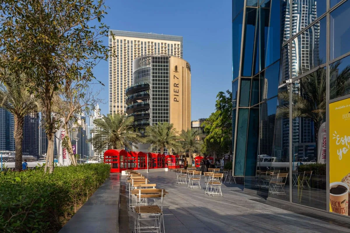 An outdoor dining area with tables and chairs beside modern glass buildings.