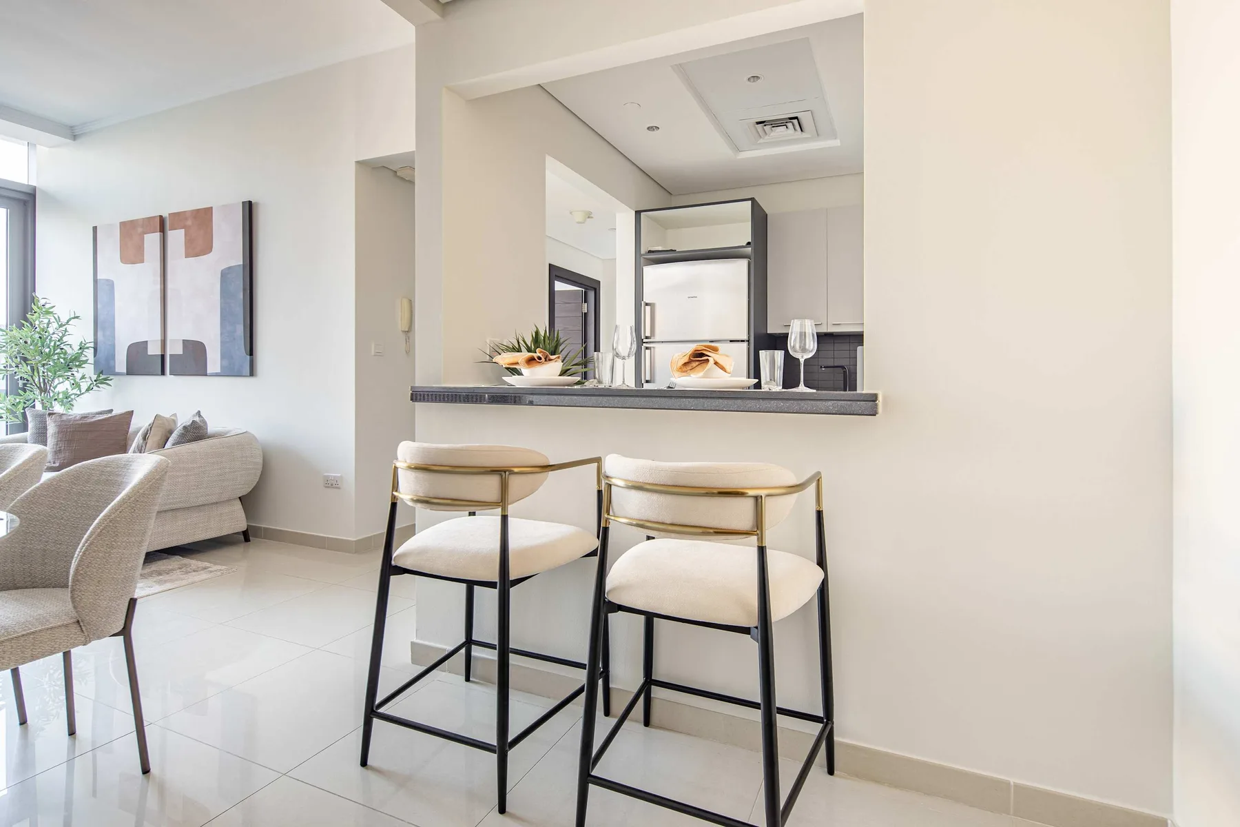 A bright open-plan living area with a counter, bar seating, and a sofa.