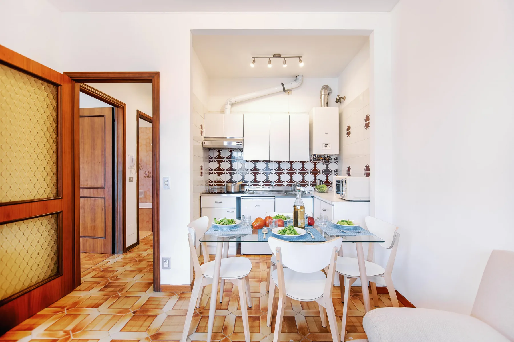 A dining area with a table and chairs sits in front of a compact kitchen.