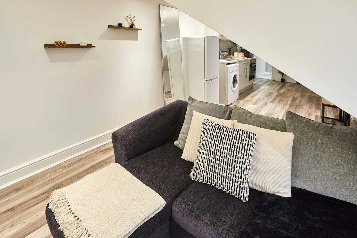 A living area with dark seating and a view into a compact kitchen.