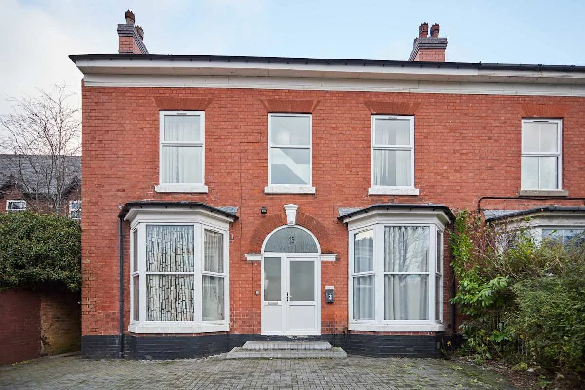 Red-brick row house with a central entrance and tall windows.
