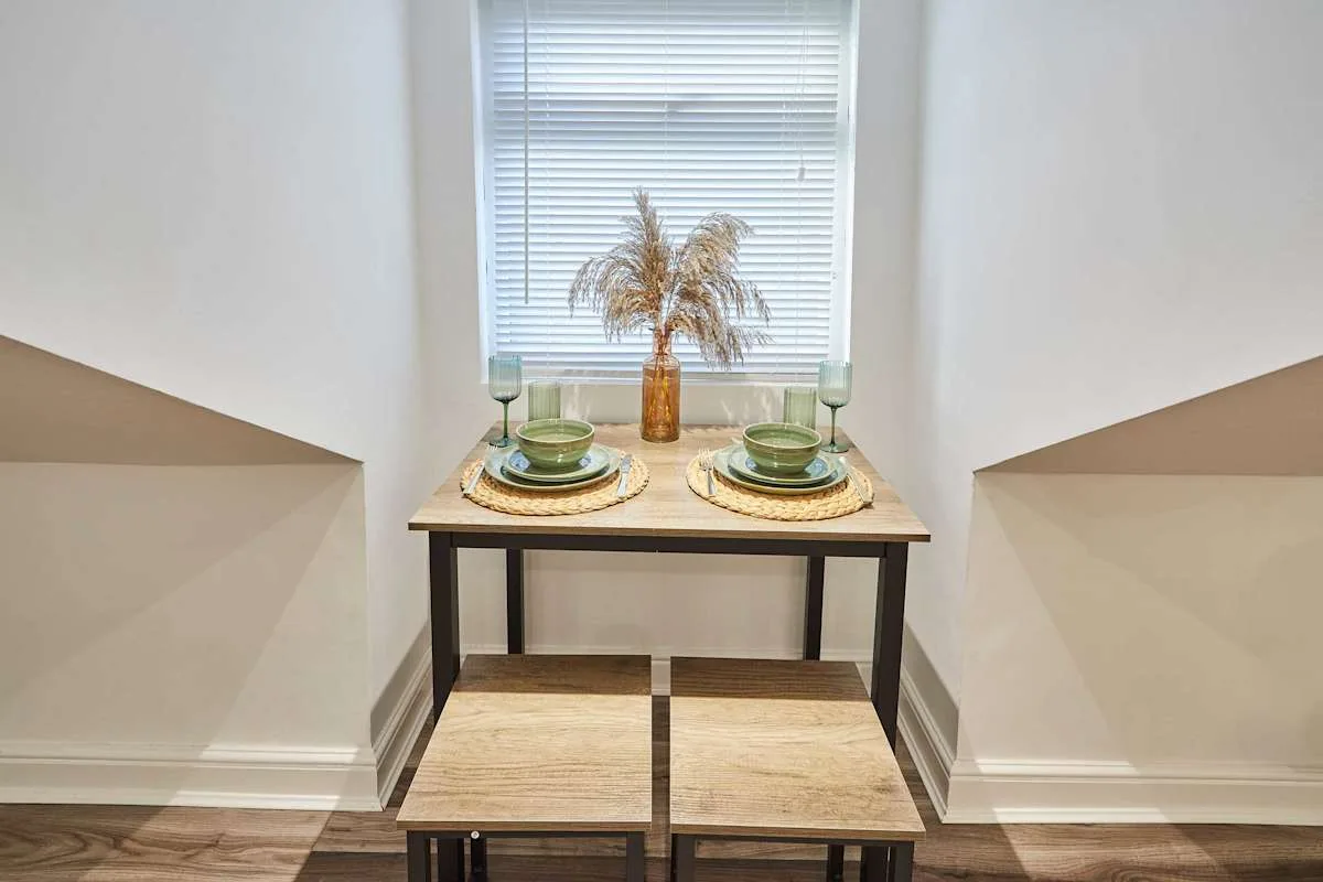 A small dining area with a table set with dishes beneath a window.