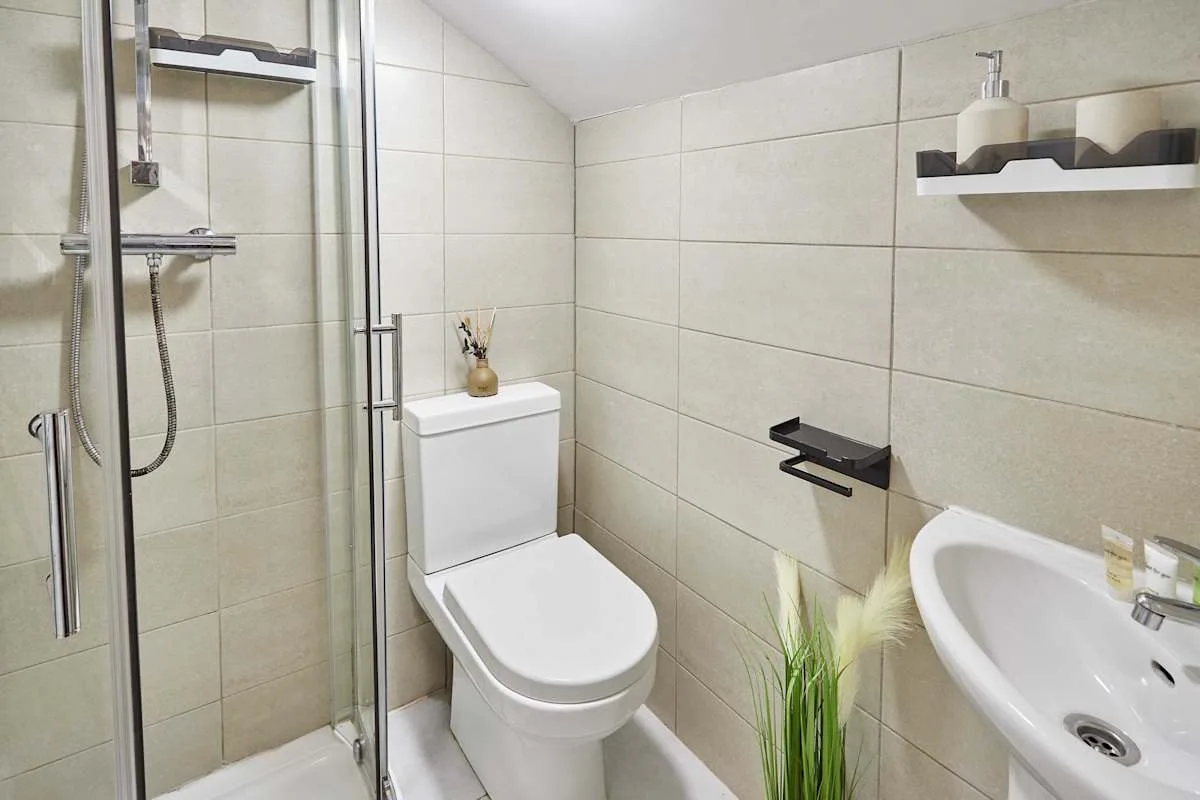 A tiled bathroom with a shower, toilet, and sink.