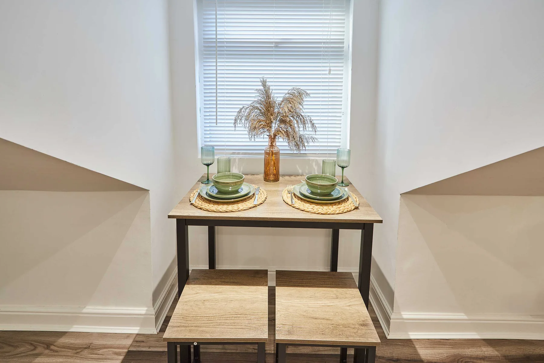 A small dining nook has a table set for two beneath a window.