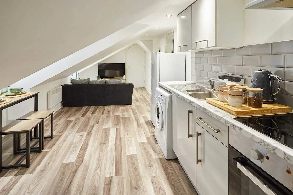 A compact kitchen and living area with a counter, appliances, and seating.