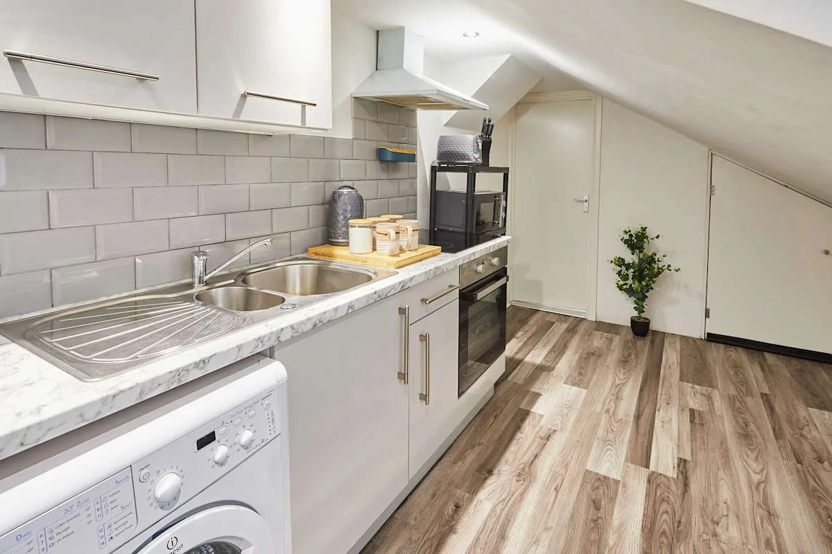 A bright kitchen with white cabinets, a sink, and wood-look flooring.
