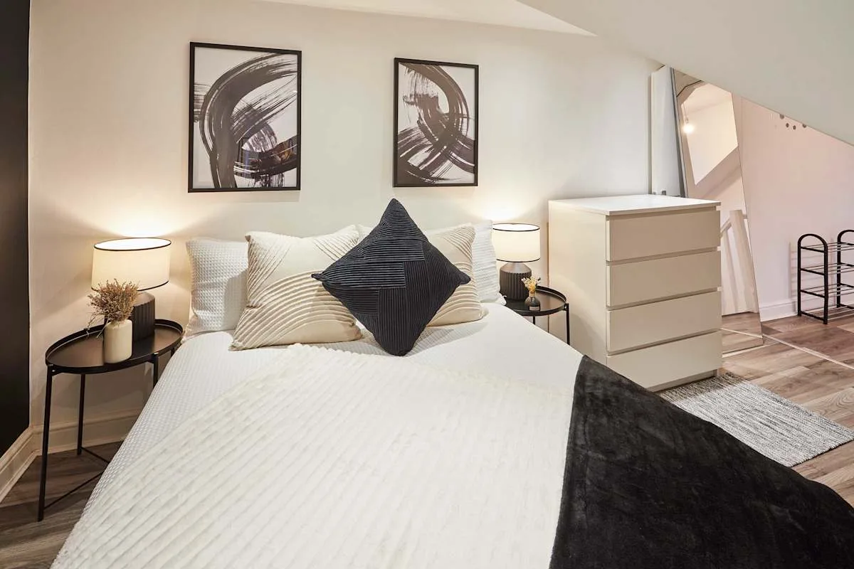A bedroom with a neatly made bed and framed artwork on the wall.
