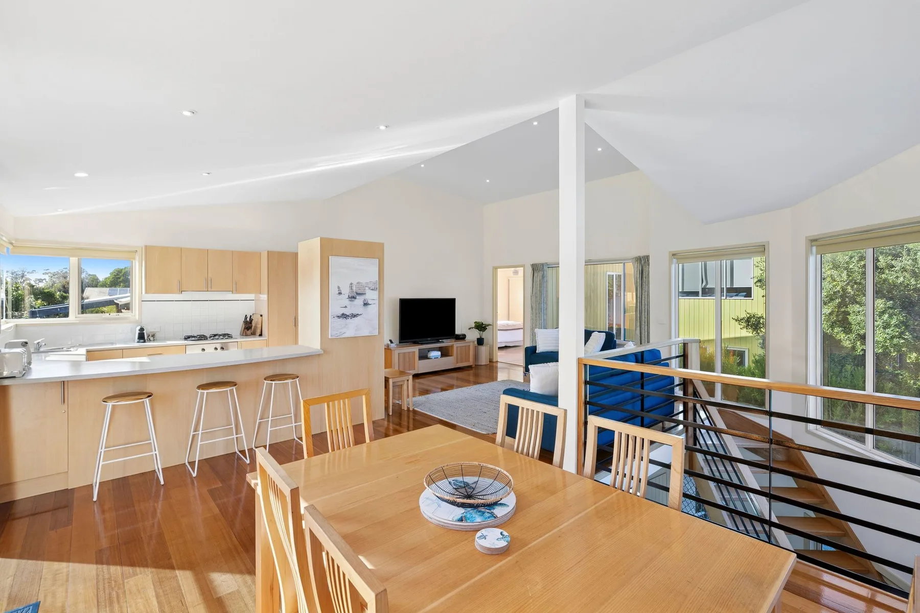 Open-plan dining and kitchen area with a wooden table and breakfast counter.