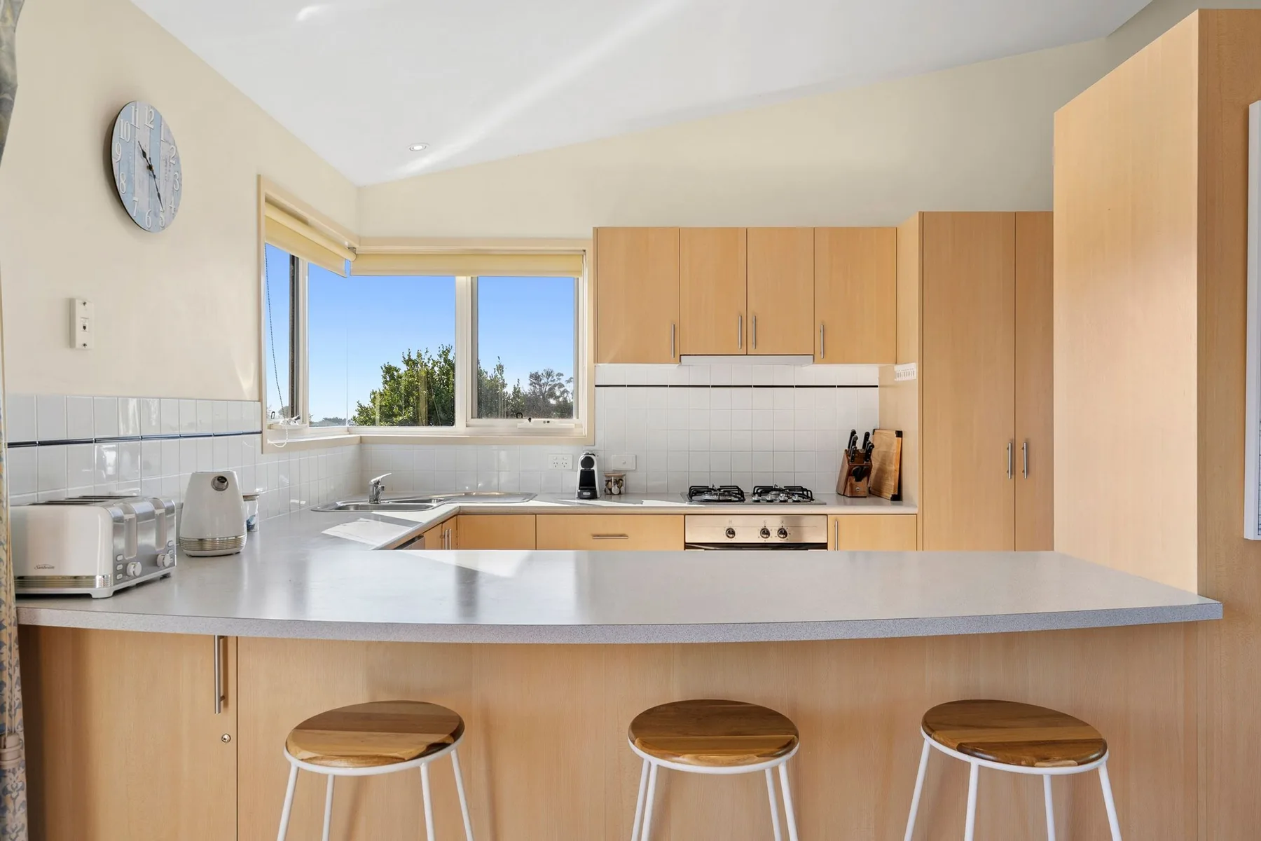 A bright kitchen with a broad counter, wooden cabinets, and a window.