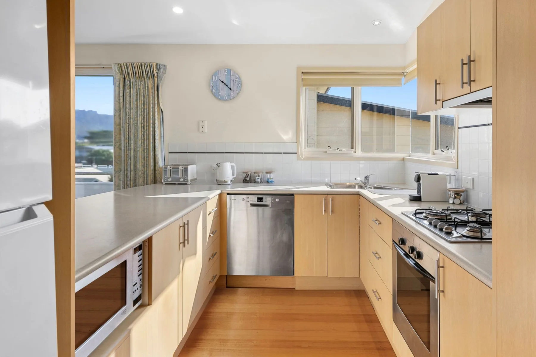A bright kitchen with light wood cabinetry, countertops, and a window.