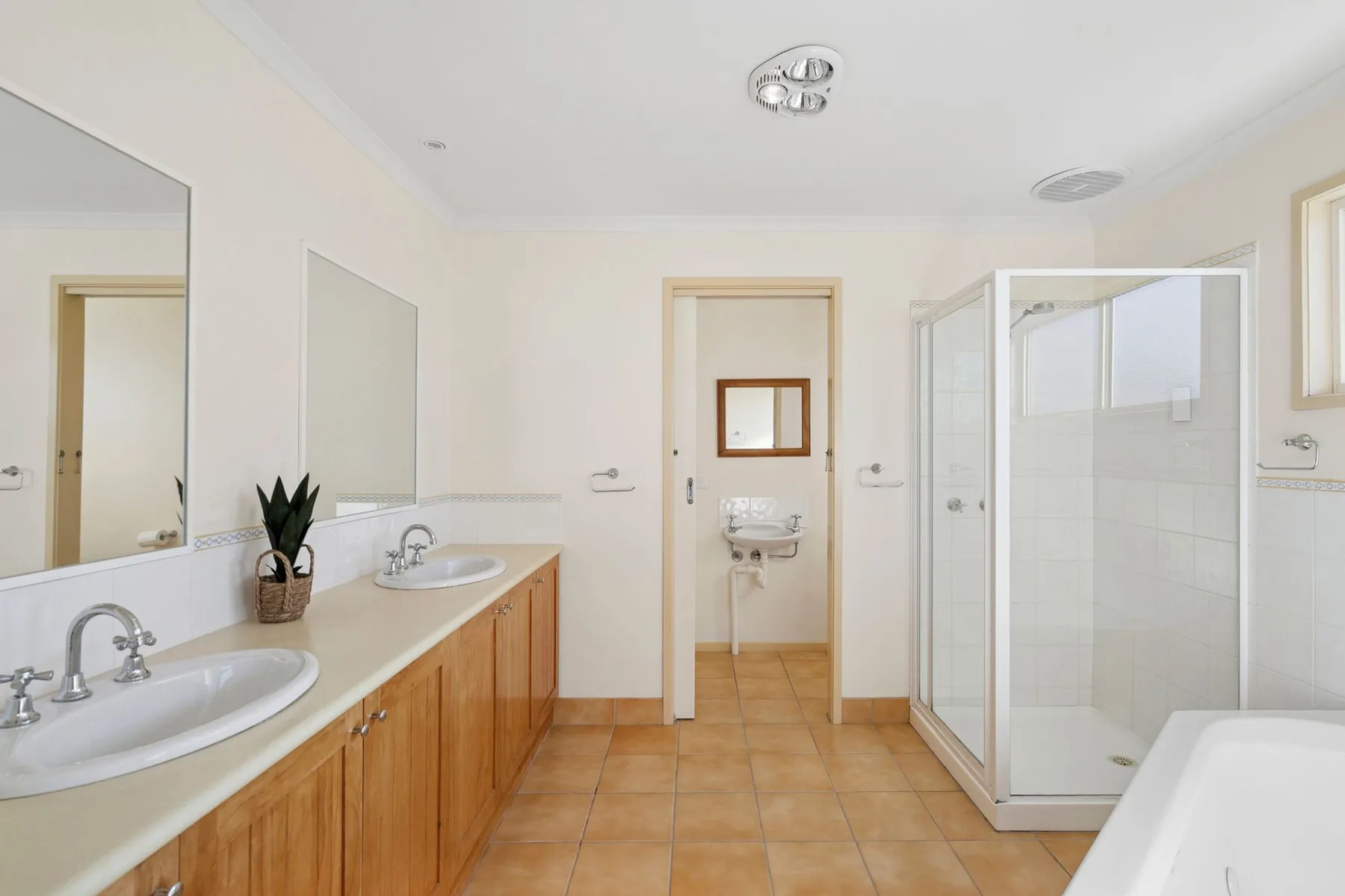 A bright bathroom with a long vanity and a glass-enclosed shower.