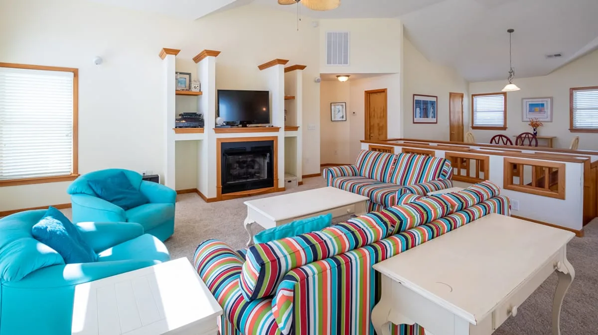 Una sala luminosa con asientos de rayas coloridas y una chimenea.