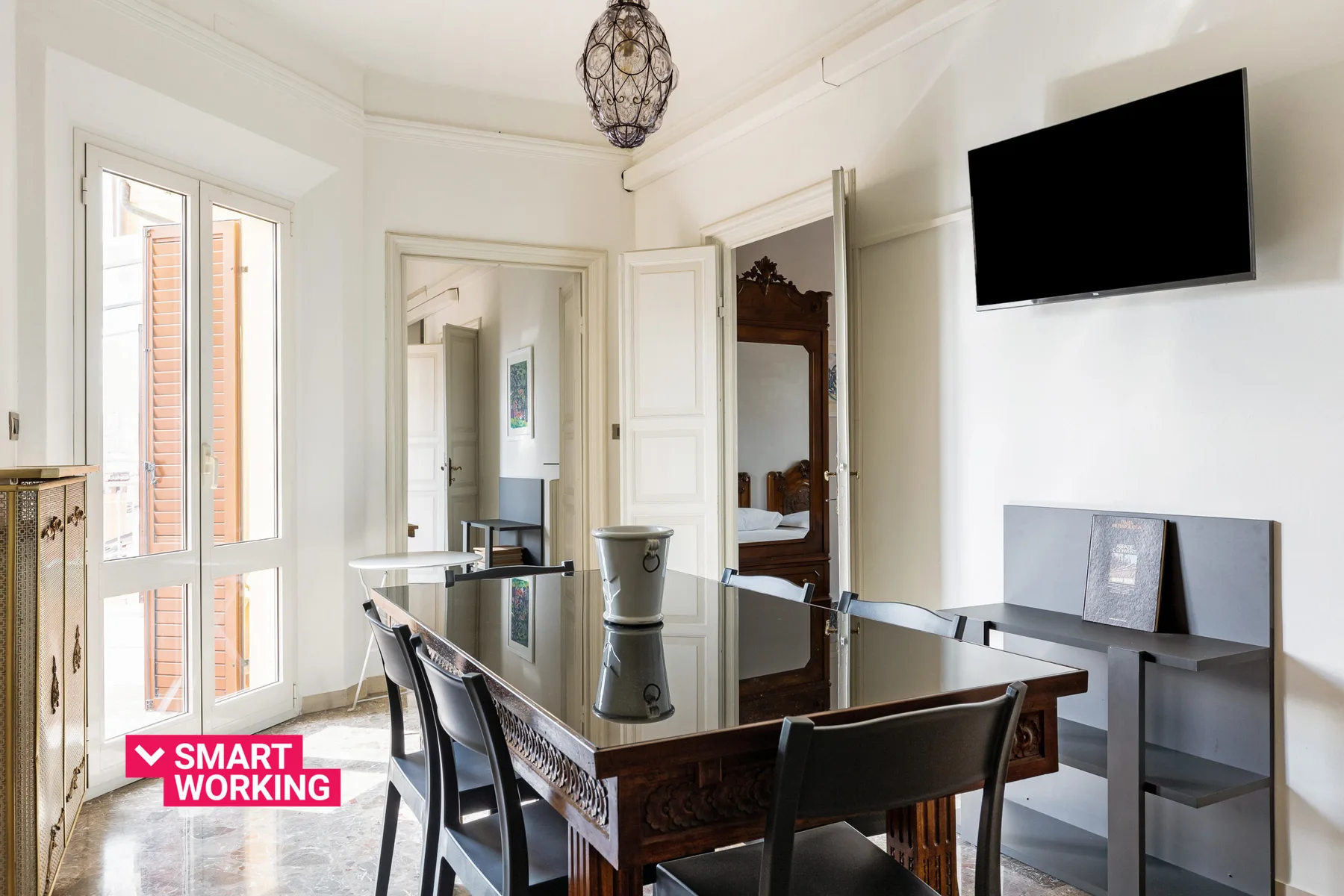 A bright dining area with a glass-topped table and tall windows.