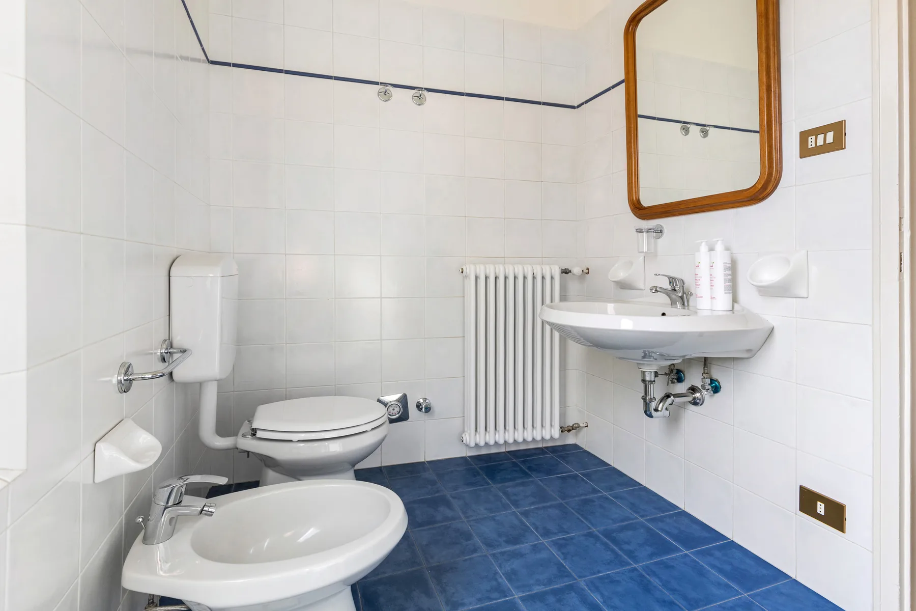 A tiled bathroom with a toilet, sink, and blue floor tiles.