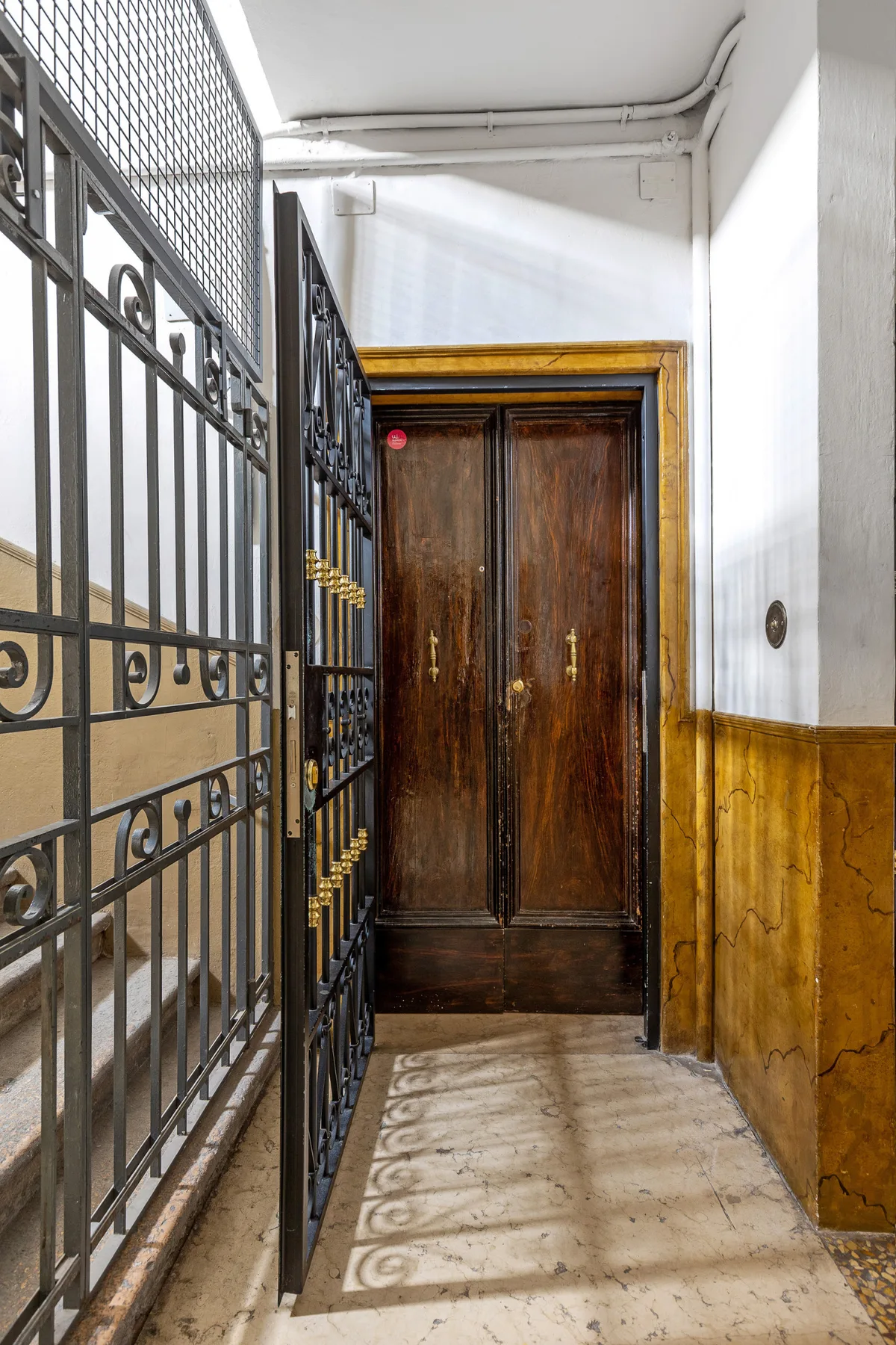 An interior entryway with a dark wooden door and a decorative metal gate.