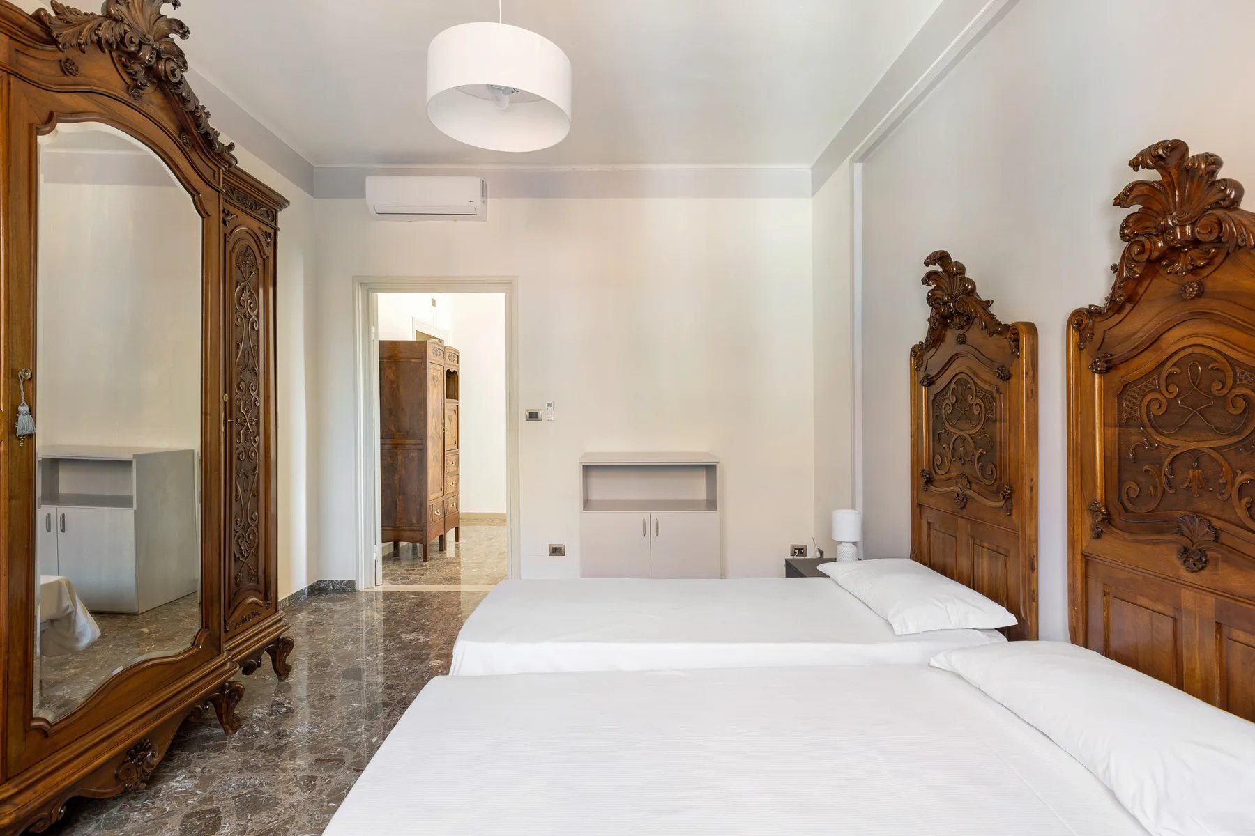 A bedroom with white bedding and ornate carved wooden headboards.