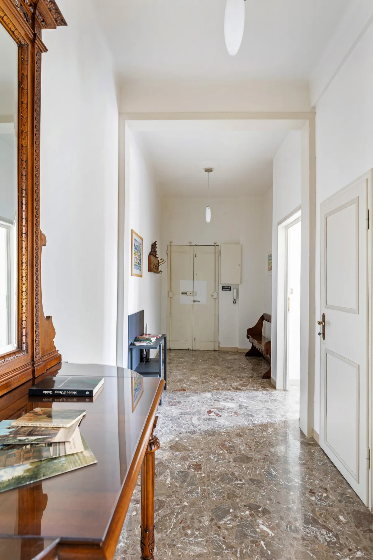 A bright interior hallway with a polished stone floor and doors at the far end.