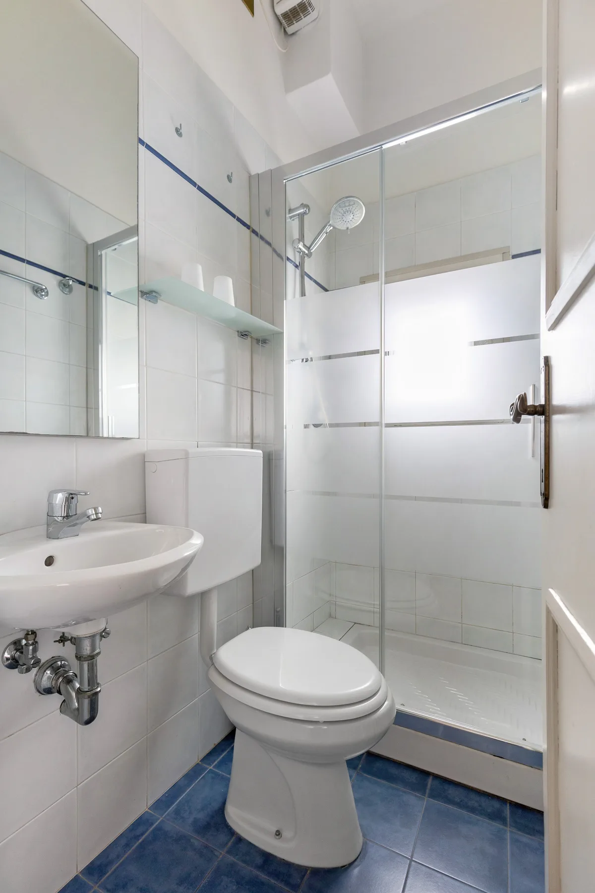 A tiled bathroom with a toilet, sink, and glass shower.