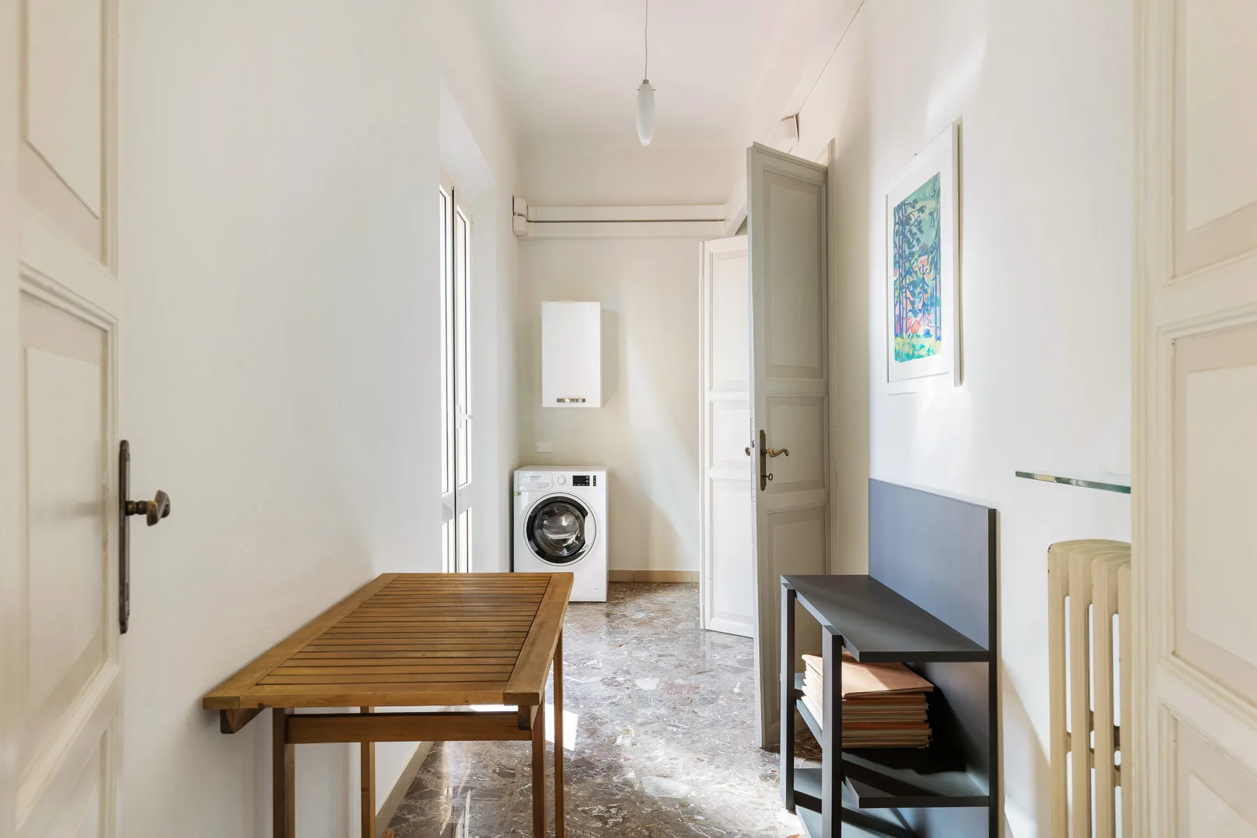 A bright hallway with a wooden table and a washing machine.