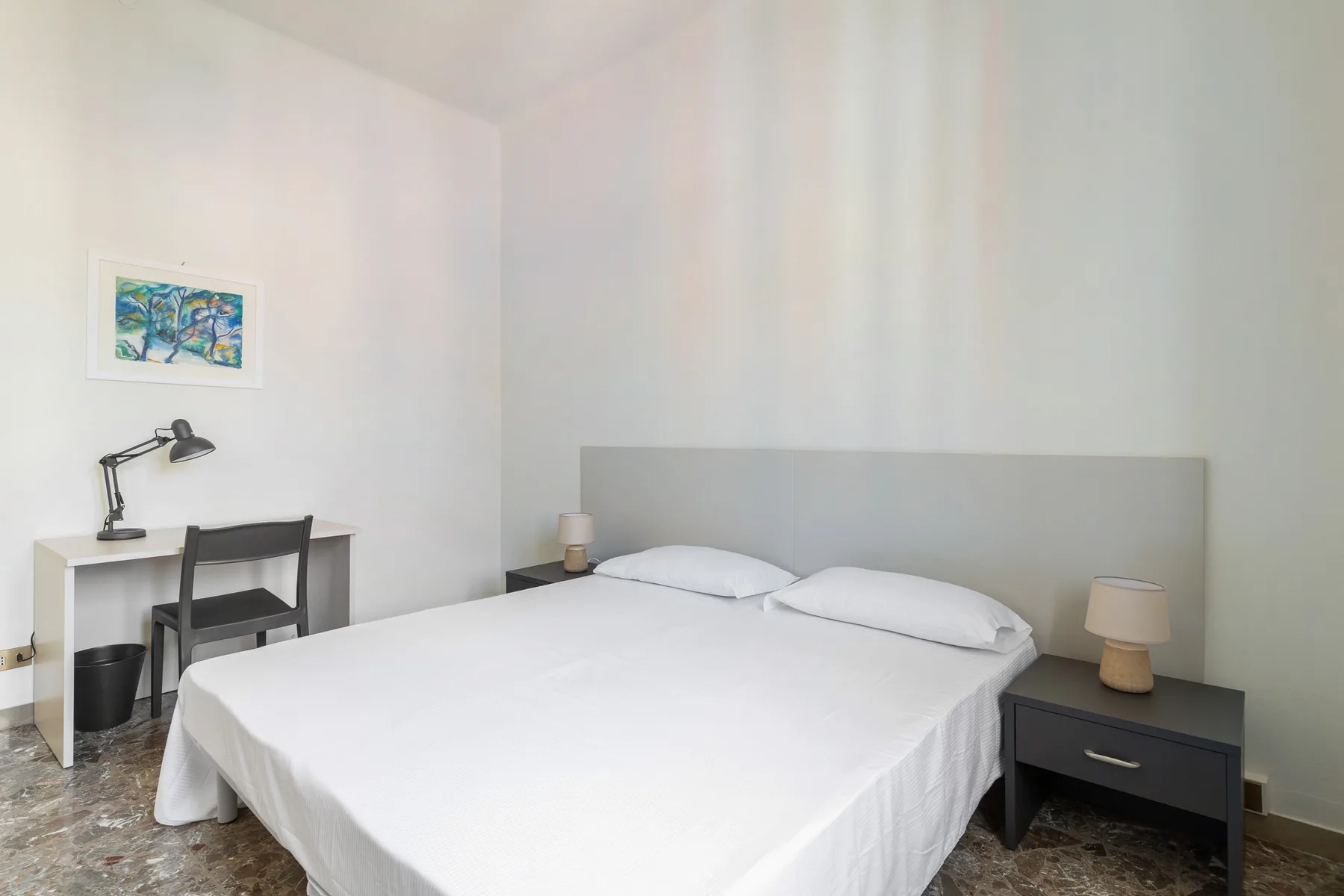 A bright bedroom with a large bed and matching bedside tables.