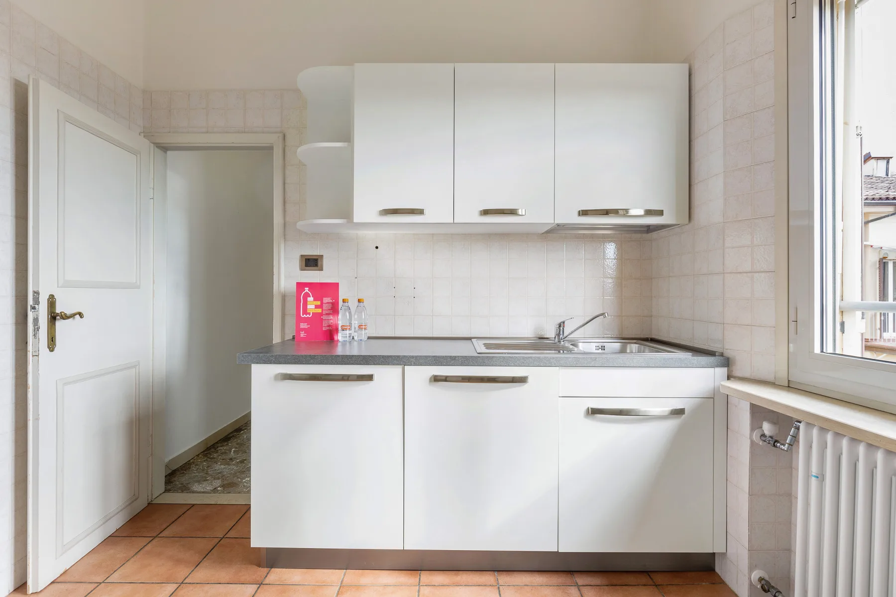 A compact kitchen with white cabinets, a countertop, and a sink.