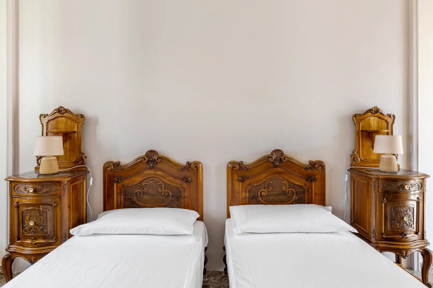 A bedroom with two single beds and matching wooden bedside tables.