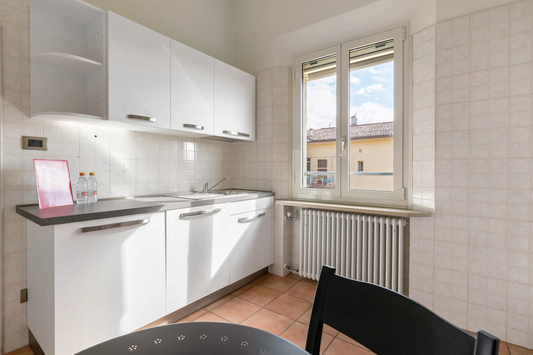 A bright kitchen with white cabinets, a countertop, and a window.