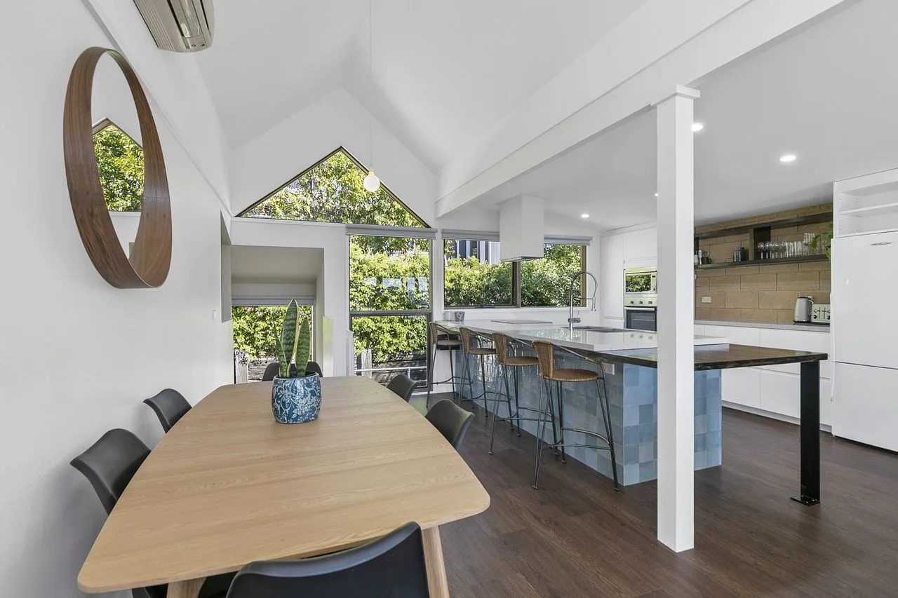 An open dining and kitchen area with a wooden table and large windows.