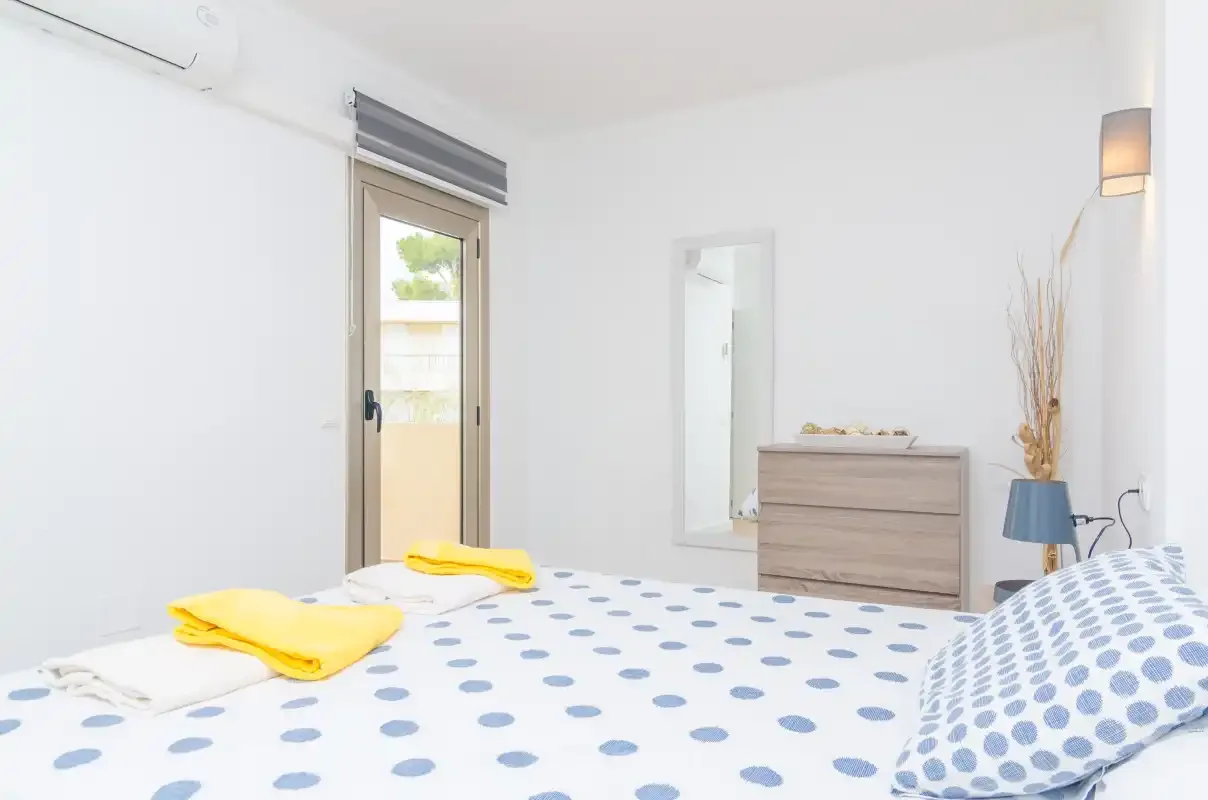 A bright bedroom with blue-patterned bedding and a wooden dresser.