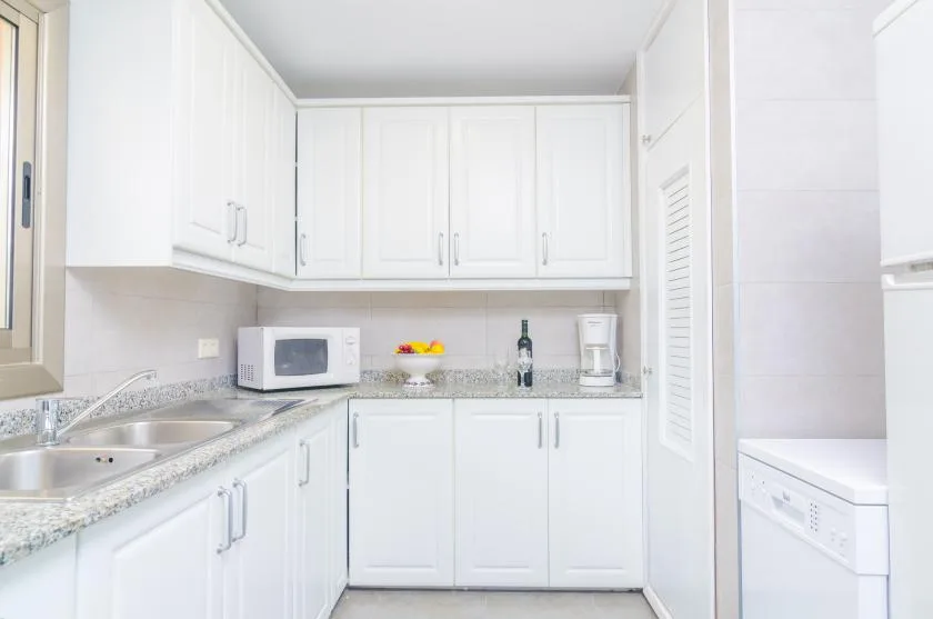 A bright kitchen with white cabinets, a sink, and countertop appliances.