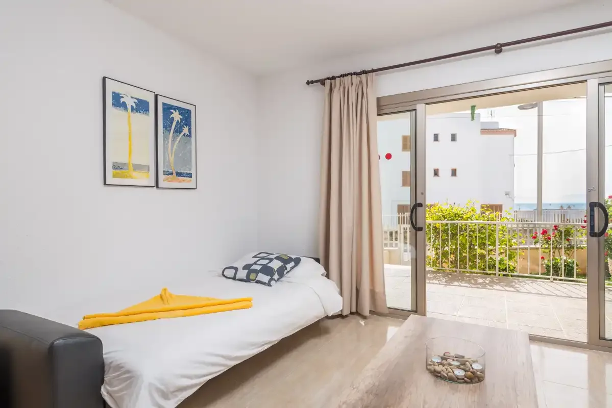 A bright sitting area with a daybed beside sliding glass doors opening to a balcony.