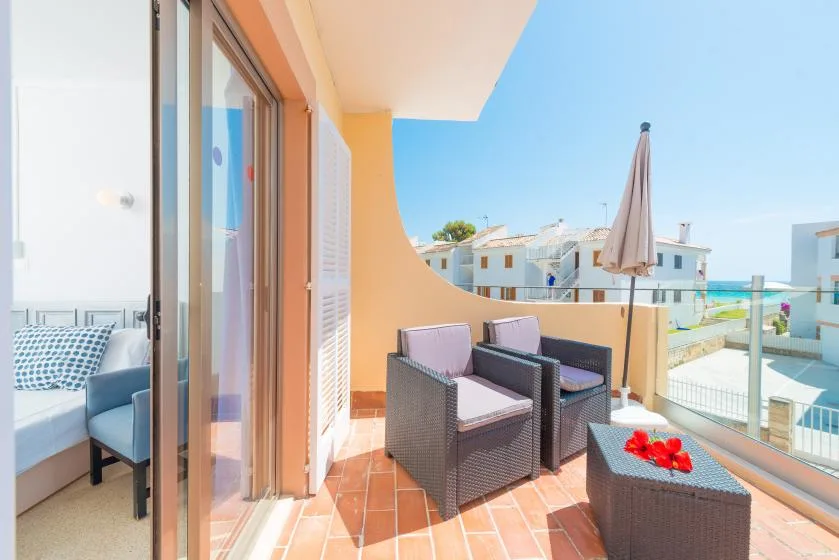 Un balcón soleado con asientos al aire libre y vistas a edificios cercanos.