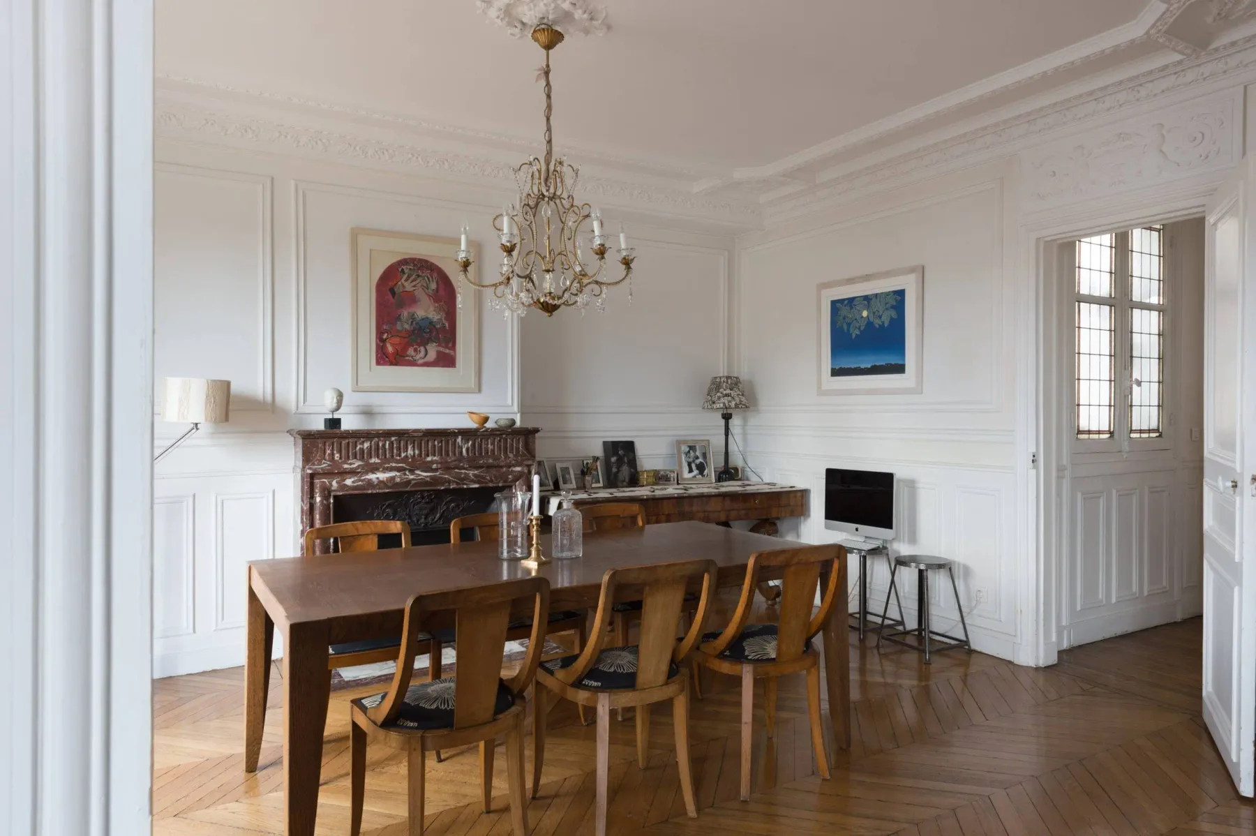 Un comedor formal con una larga mesa de madera y una lámpara de araña.