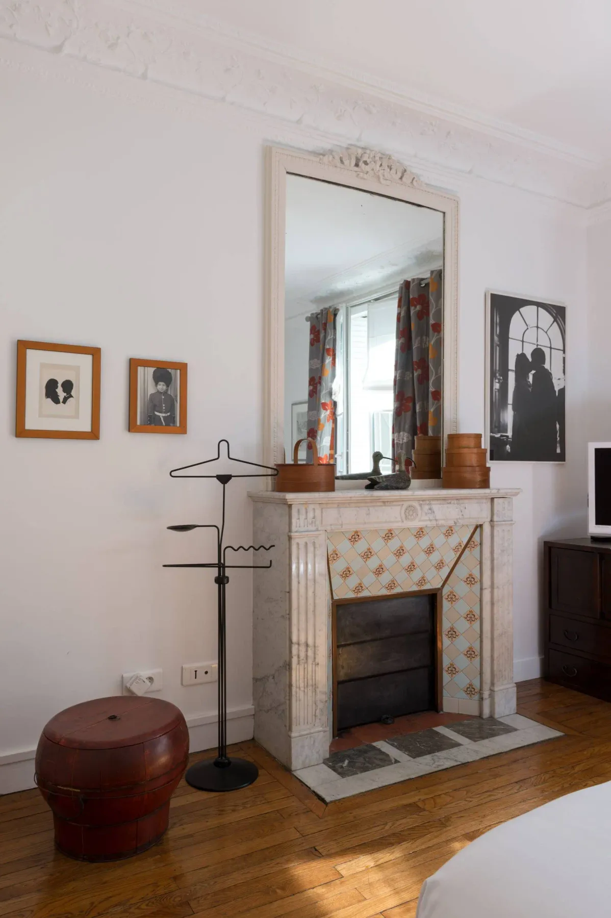 Una zona de dormitorio con una chimenea de azulejos y un espejo grande.