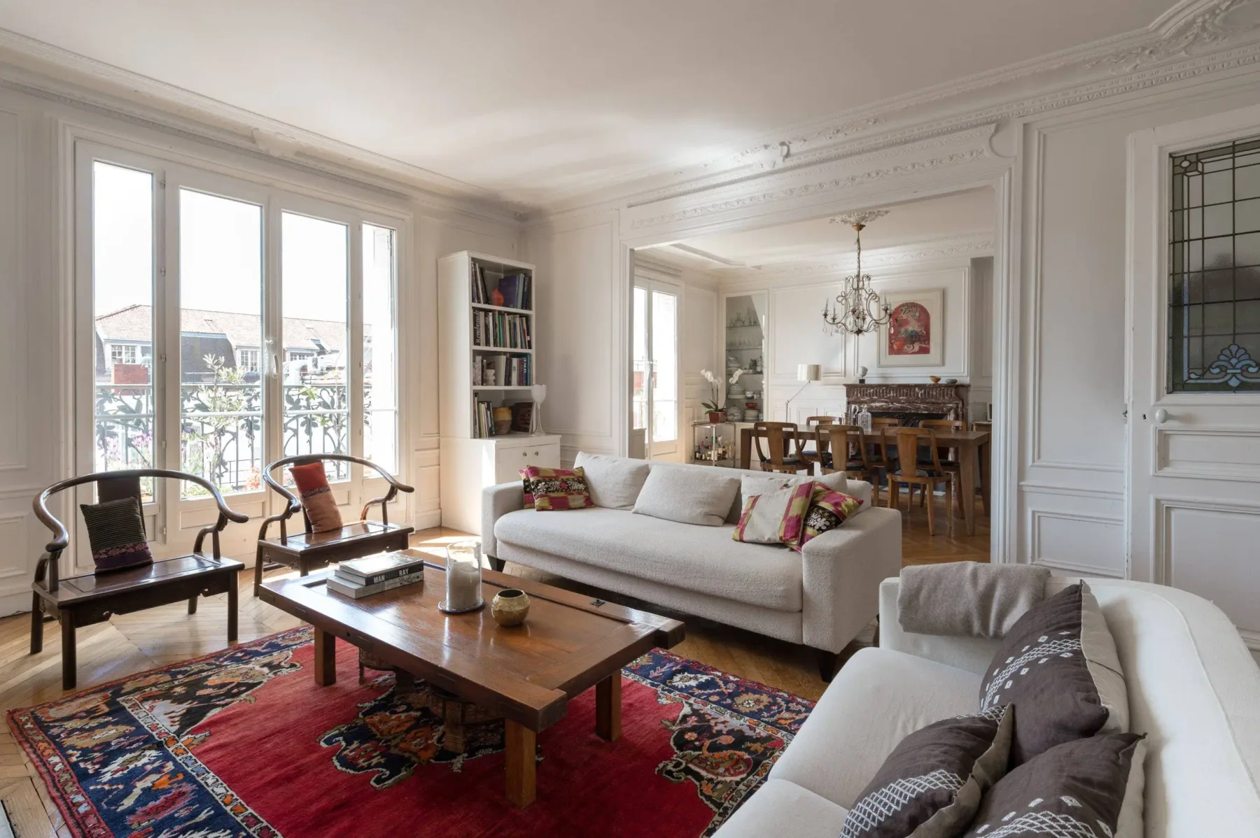 Una sala luminosa con asientos alrededor de una mesa de centro y ventanas altas.