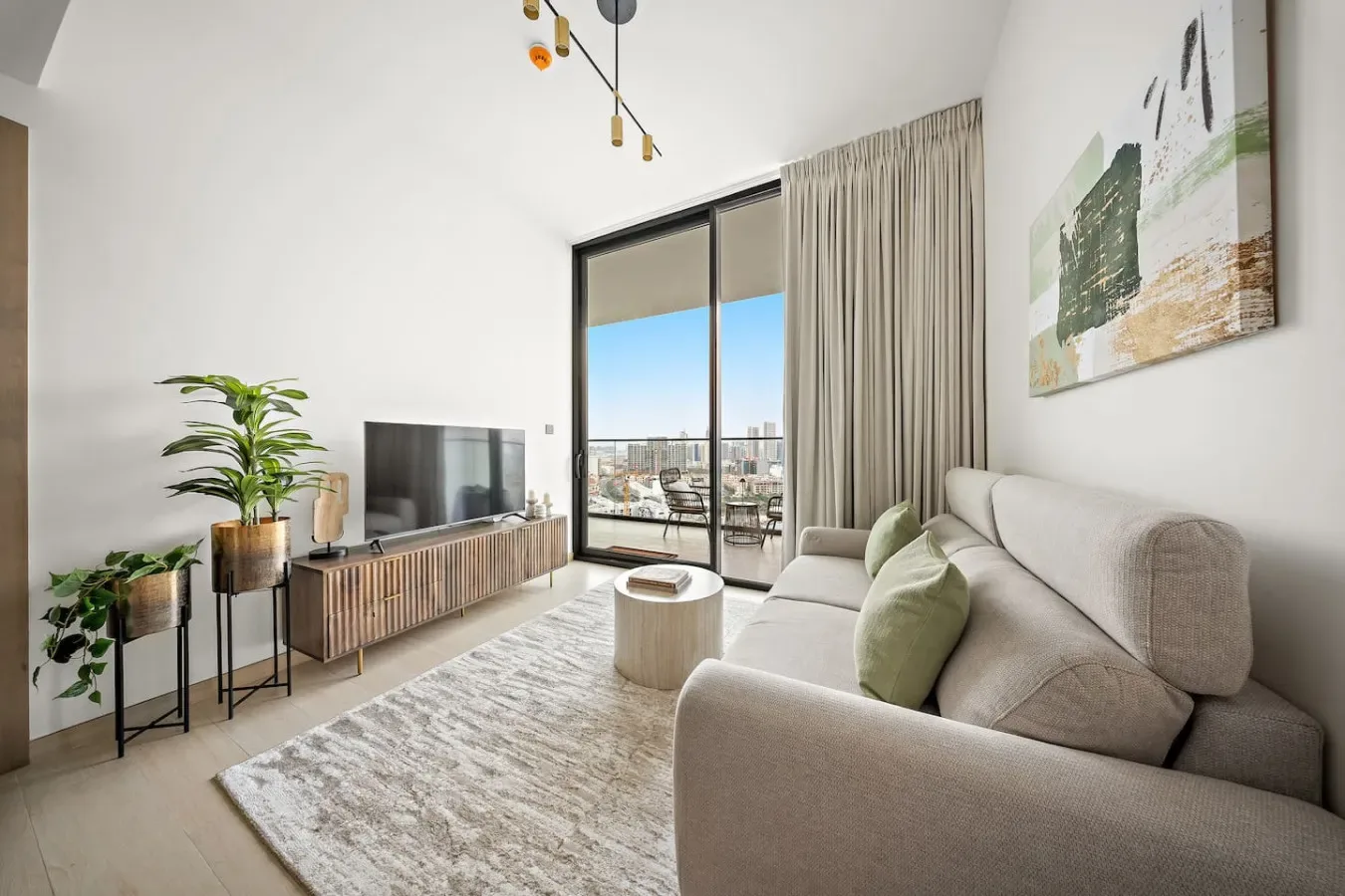 Una sala luminosa con sofá, televisor y grandes puertas de vidrio.