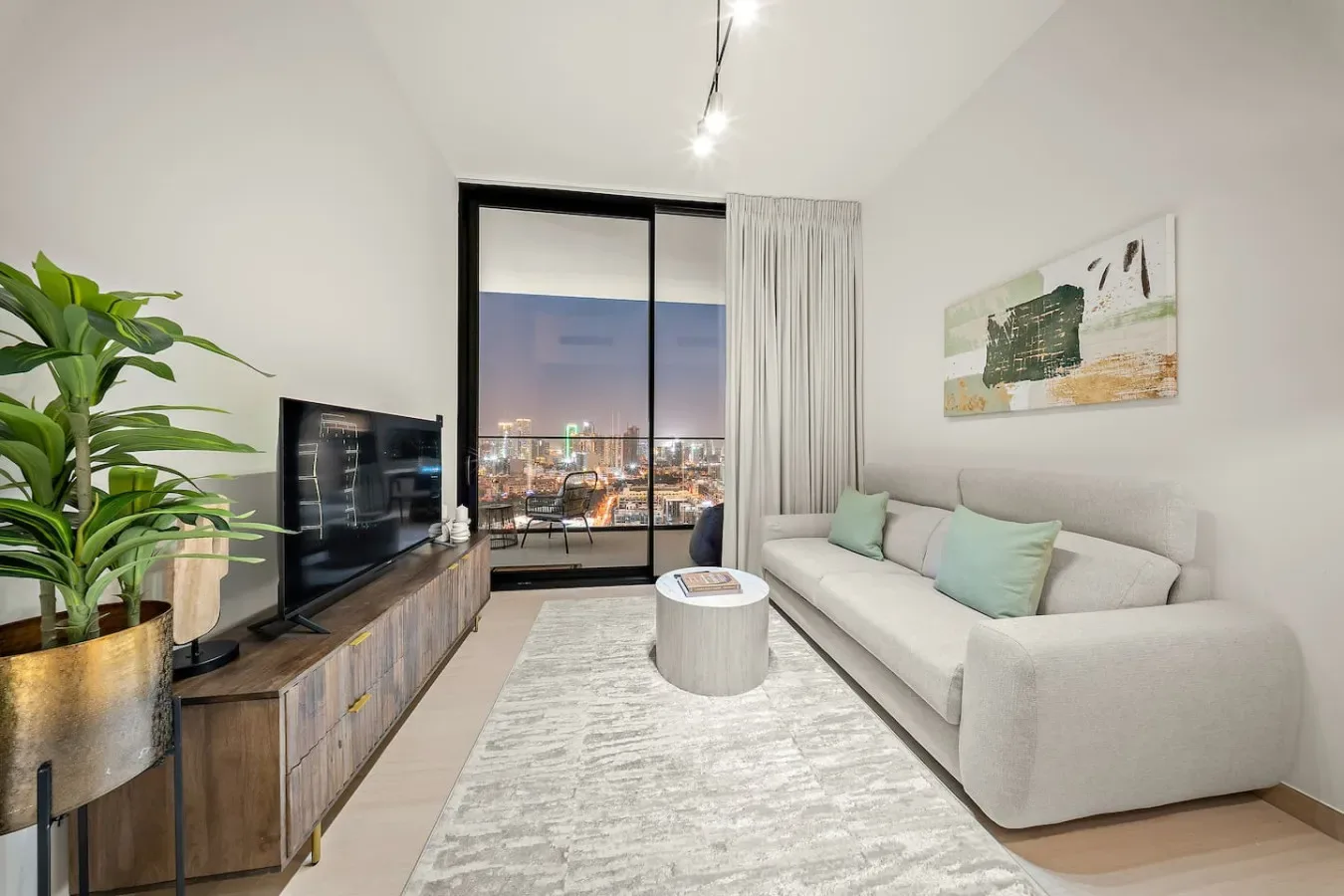 Una sala de estar moderna con asientos, un televisor y vistas de la ciudad por la ventana.