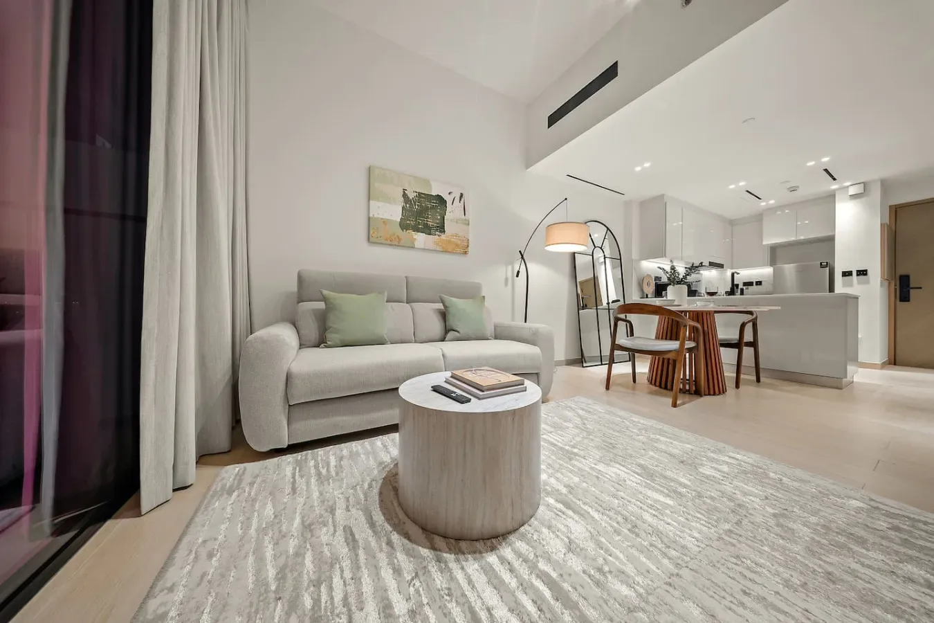 Sala de estar con sofá y mesa de centro redonda junto a una cocina abierta.